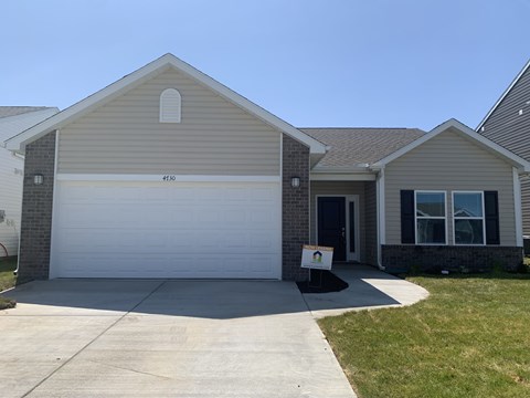 a house with a white garage door and a sign on the driveway